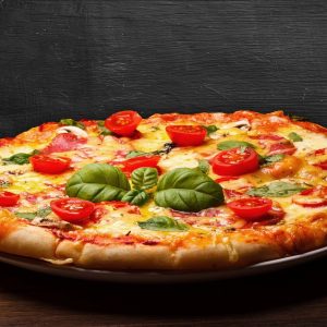 Zeit für Pizza: Pizza mit Tomaten, Basilikum und Käse auf einem Teller.