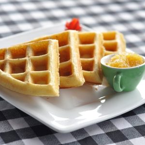 Waffeln mit süßem Aufstrich auf einem karierten Tuch.