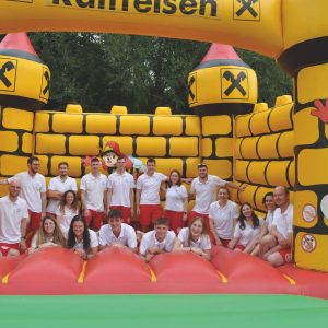 Eine Gruppe von Menschen in weißen und roten Uniformen posiert zusammen in einer großen gelben und roten aufblasbaren Burg.