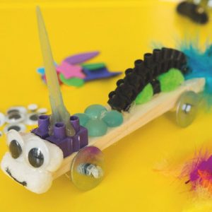 Kreatives Schulprojekt mit Bastelmaterialien auf gelbem Hintergrund.
